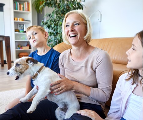 image of woman laughing with children and a dog