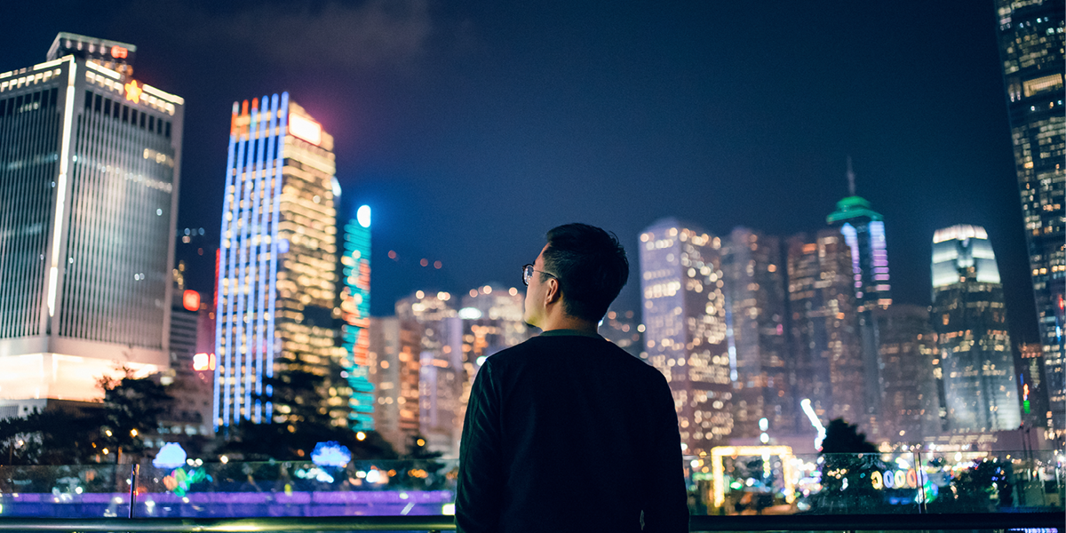 Man looking out at skyscrapers lit up at night